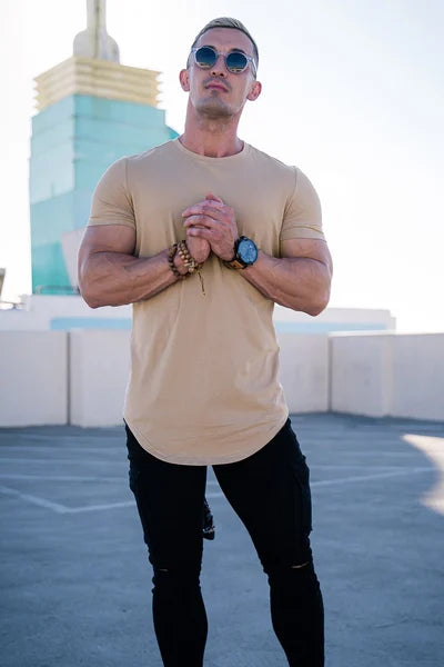 Ein Mann trägt ein khakifarbenes Essential T-Shirt mit tiefem Schnitt